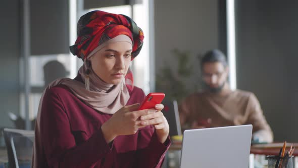 Beautiful Woman in Hijab Texting on Smartphone in Office