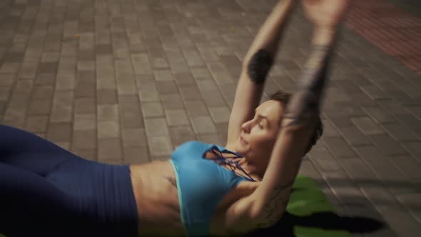 Young Girl Doing Exercise on the Abdominal Muscles in the Evening Park