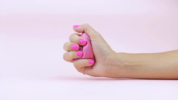 A Female Hand Squeezes and Unclenches a Pink Silk Heart