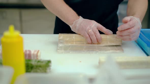 Cook Prepares a Japanese Roll with Rice and Sesame Seeds