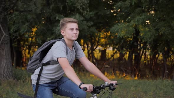 Teenage Boy Rides Bike in City Park at Sunny Day. Healthy Lifestyle Concept
