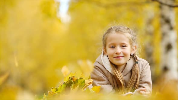 Portrait of Adorable Little Girl with Yellow Leaves Bouquet in Fall. Beautiful Smiling Kid Lying