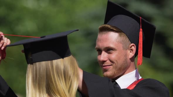 Caring Male Graduate Adjusting Tassels on Girlfriend's Cap Couple in Love