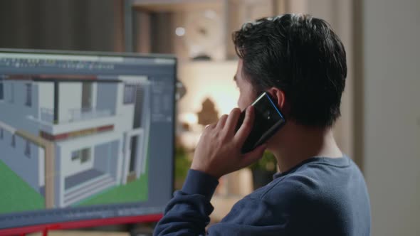 Close Up Of Asian Male Engineer Talking On Smartphone While Designing House On A Desktop At Home