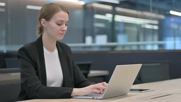 Businesswoman Showing Thumbs Down While Using Laptop