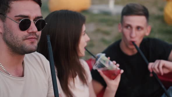 Two European Boys Are Smoking and a Girl Is Drinking a Cocktail