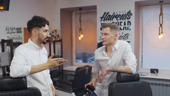 Two Young Barbers Communicating in Empty Barber Shop