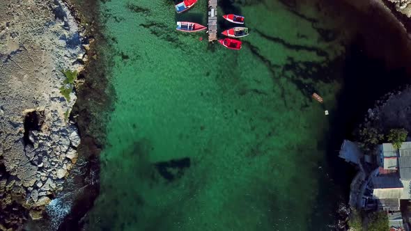 Dolly in overhead view of a small wooden walkway with fishing boats on either side, Kanoa Beach, Cur