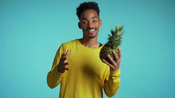 Playful Young African American Man Throws Hand to Hand Fresh Pineapple. Healthy Exotic Lifestyle 