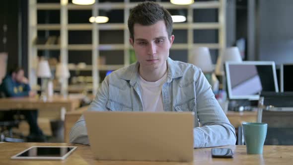 Young Male Designer Using Laptop in Modern Office