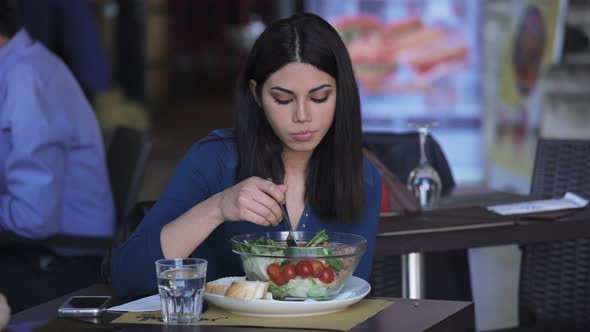 Pretty asian woman alone eating salad at restaurant