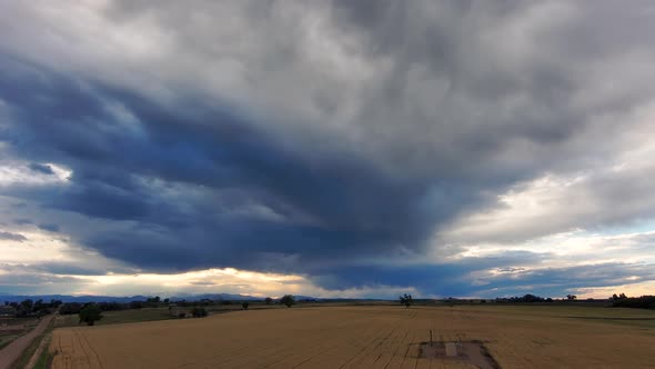 A drone rises above fields of wheat and corn to show the majestic mountains in the distance. Colorad