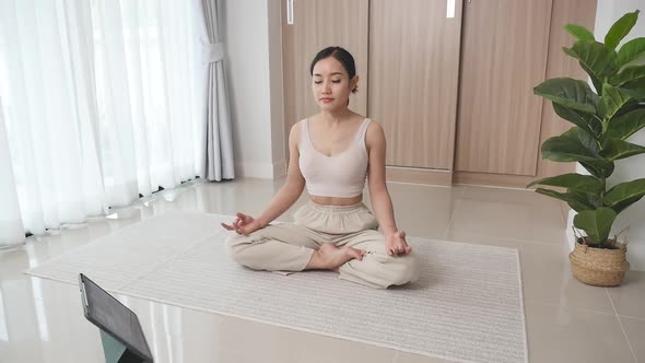 Woman studying online meditation on the floor in the living room to improve cons