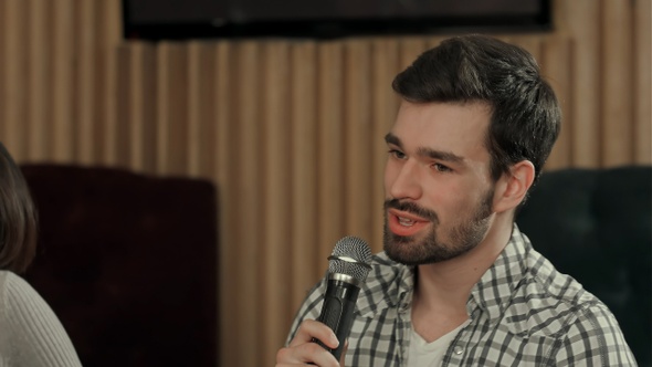 Young man is singing a song in club