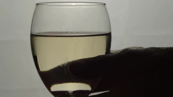 Hand holding glass of white wine silhouette close up shot