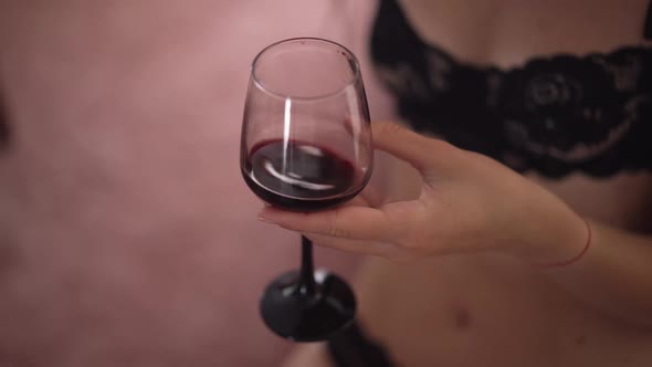 Closeup Red Wine Shaking in Slow Motion in Glass As Unrecognizable Slim Young Woman in Black