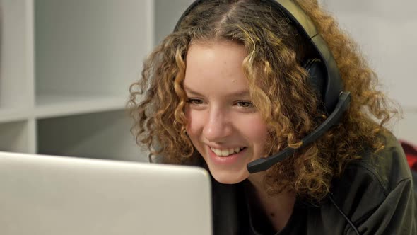 Teenage Smiling Girl Using a Laptop and Wearing Headphones Technology and Leisure Concept