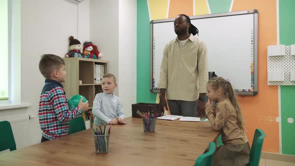 An African American Teacher Teaches a Group of Children in the Classroom in a Playful Way
