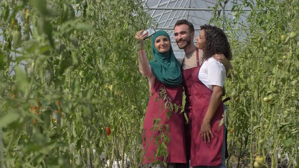 Joyful Diverse Gardeners Taking Selfie in Hothouse