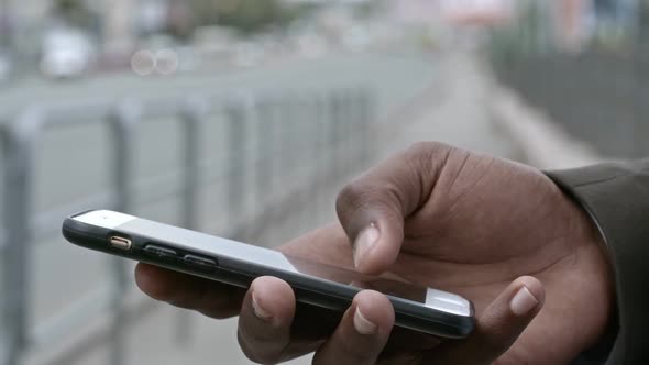 Close Up of Hand of African Man Using Smartphone