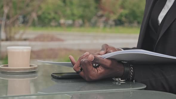 Unrecognizable Businessman Looking at Documents in Outdoor Cafe