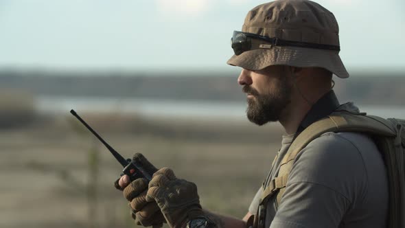 Closeup Side Shot of Seriouslooking Bearded Male Soldier Hunter or Guard Standing in Plain Area or