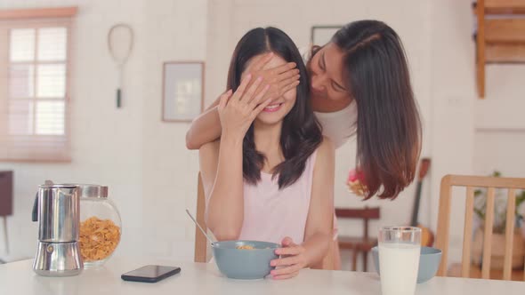 Asian Lesbian lgbtq women couple giving present home.