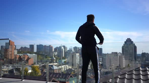 Wide Shot Confident Middle Eastern Sportsman Stretching Legs Standing at Glass Fence on Building