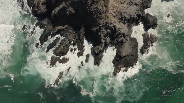 Aerial view of waves crashing on rocks.