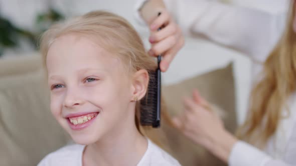 Cheerful Woman Brushing Hair of Little Girl