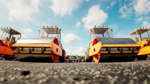 An endless row of yellow big road rollers standing in the row.  Heavy machines.