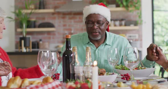 Happy diverse male and female senior friends celebrating meal at christmas time