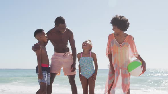 Portrait of smiling african american family embracing on sunny beach