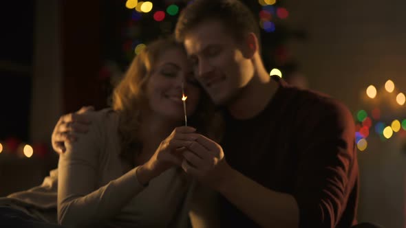 Passionate Couple Kissing Near Christmas Decorations With Bengal Light in Hands