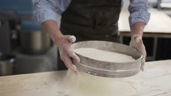 Hands Holding Sieve and Sifting Flour at the Kithen