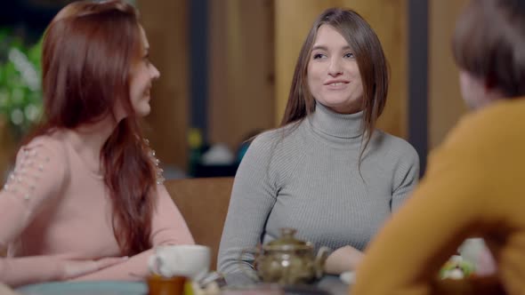 Middle Shot of Beautiful Slim Excited Young Woman Talking with Friends in Cafe in Slow Motion