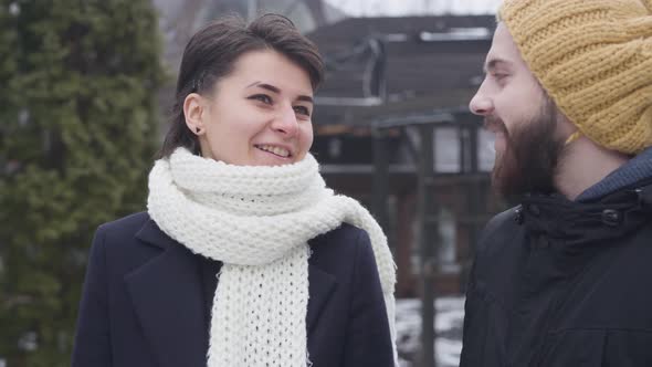 Close-up of Young Caucasian Couple Strolling Along Winter Street. Happy Man and Woman Talking and