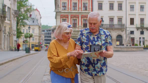 Senior Grandmother and Grandfather Tourists Looking for a Place to Go in New City Using Paper Map