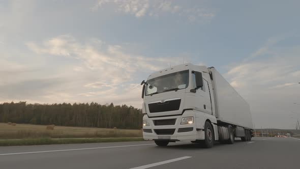 White truck with trailer driving on road, cargo transportation