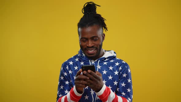 Happy Absorbed African American Smiling Man Surfing Social Media Messaging Online on Smartphone