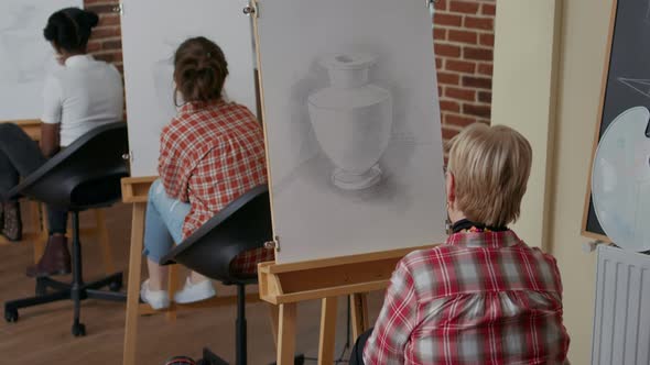 Elder Student Using Pencil to Draw on Canvas in Art Class