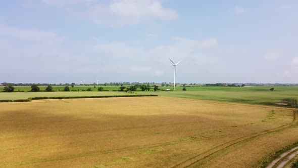 Drone Footage of Wind Turbines in Patchwork Fields with Clouds Rolling Across