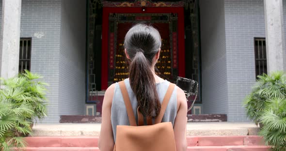 Woman holding camera to take video and walk into chinese temple
