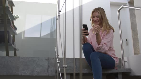 Caucasian woman smiling at her smartphone in hotel