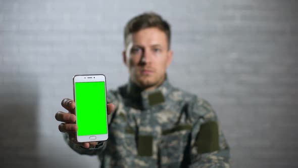 Male Soldier in Uniform Showing Smartphone With Green Screen at Camera, App