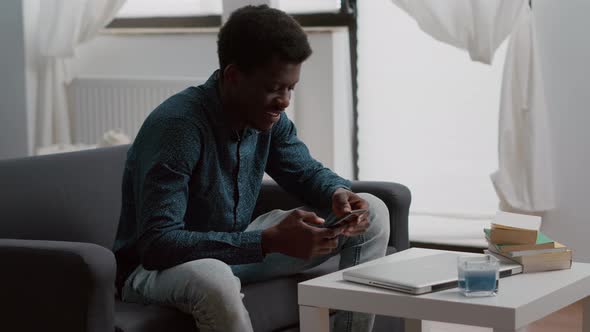 Positive Authentic Black African American Man Smiling While Using a Smartphone