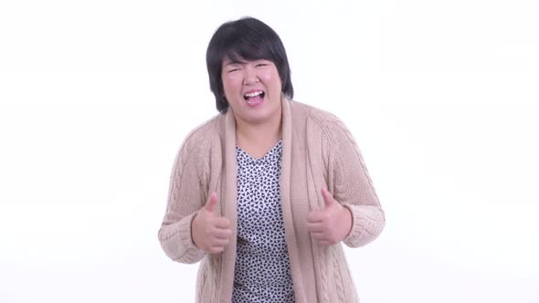 Happy Overweight Asian Woman Giving Thumbs Up and Looking Excited for Winter