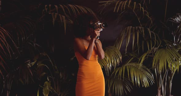 Woman With Afro Hair In Orange Dress Using Vintage 8Mm Camera