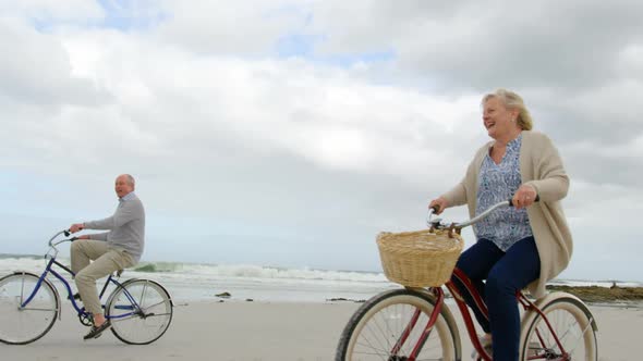 Side view of old caucasian senior couple riding bicycle at beach 4k