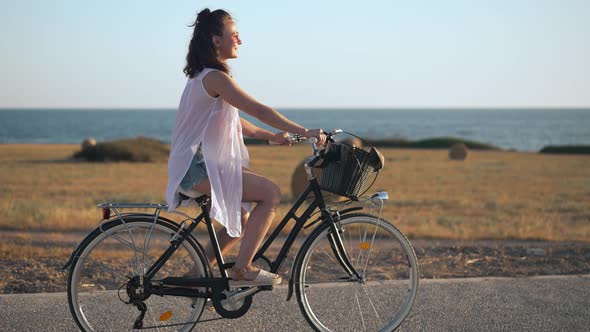 Excited Young Beautiful Bicyclist Raising Hands Riding Bike in Slow Motion at Background of Cyprus